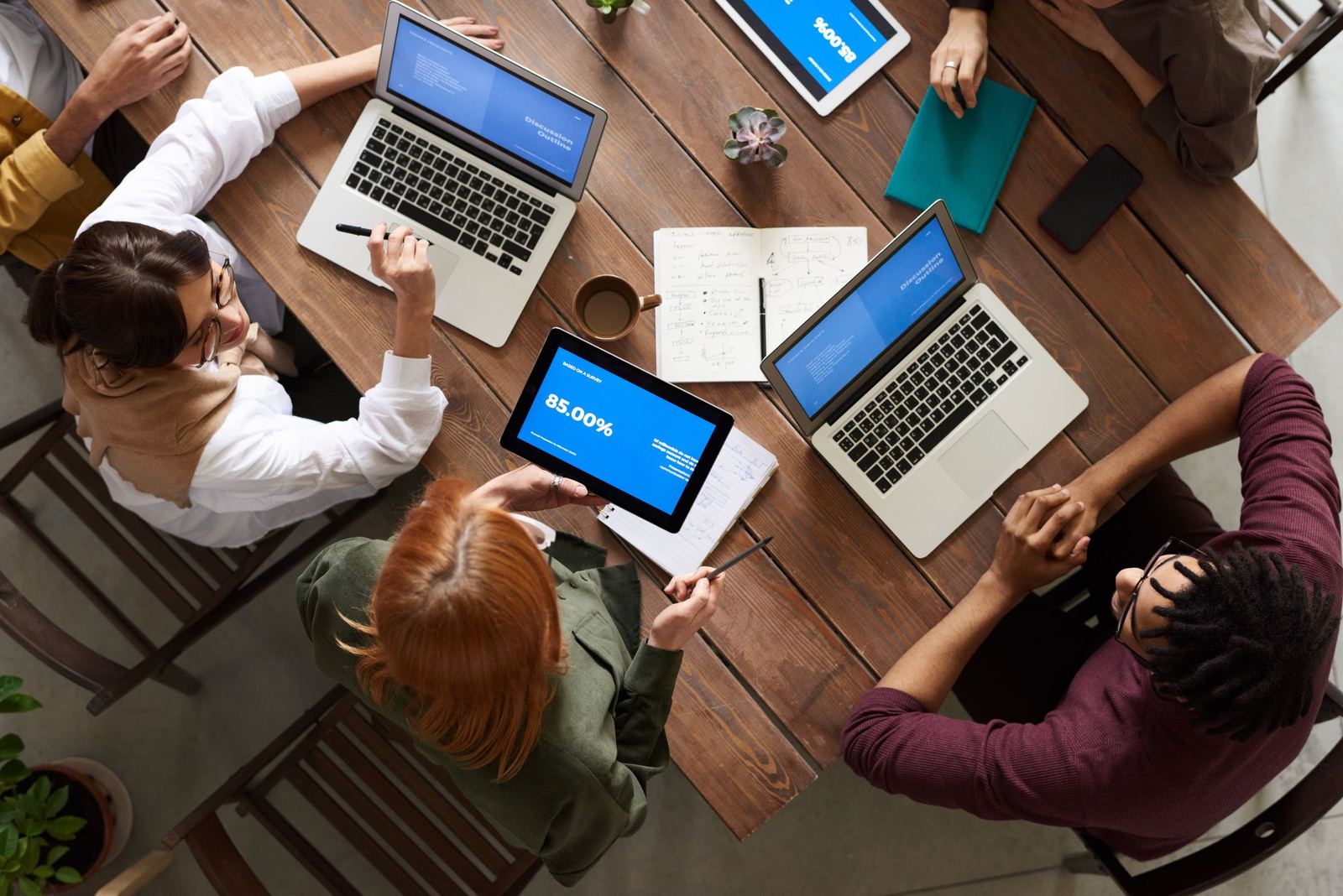Team working together around a table covered in laptops and notes