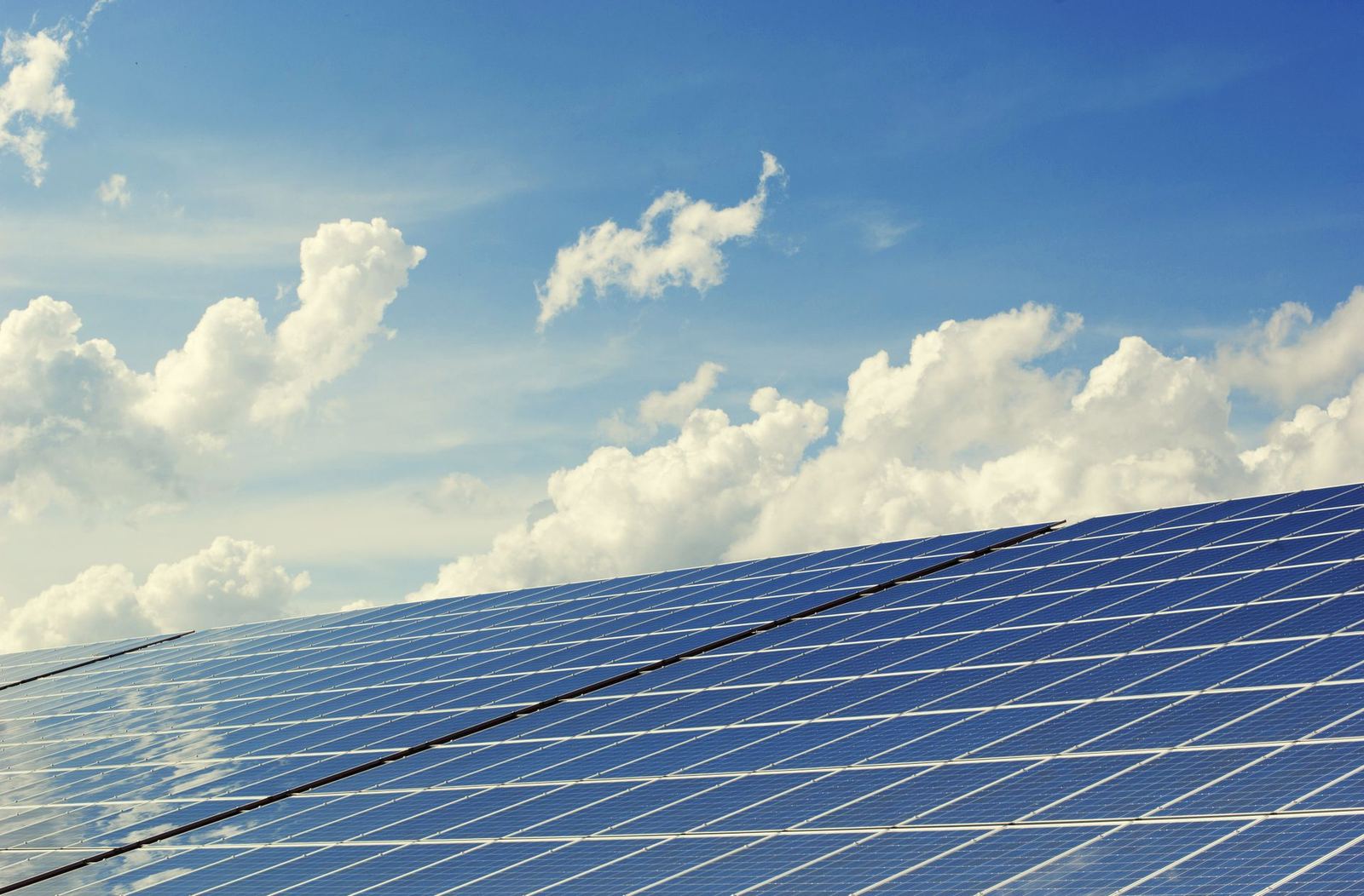 Solar panel array under a blue sky with clouds