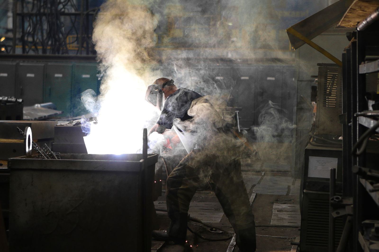 Welder working through smoke in a metal fabrication workshop